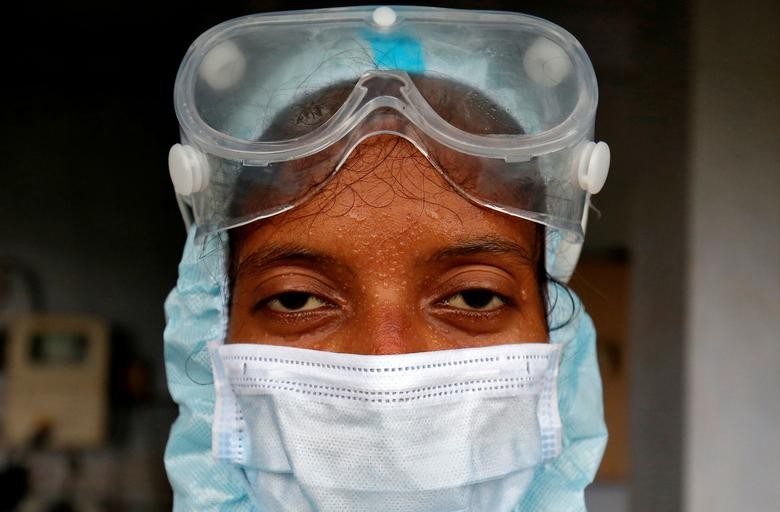 Beads of sweat run down the forehead of a healthcare worker wearing protective gear after she took swabs for a rapid antigen test from residents at a residential apartment in Ahmedabad. REUTERS/Amit Dave